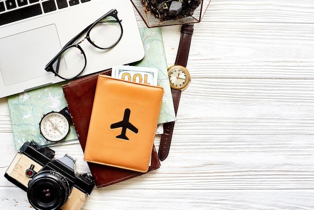 Travel and wanderlust concept planning summer vacation background flat lay space for text map compass photo camera glasses wallet watch laptop on white wooden table top view