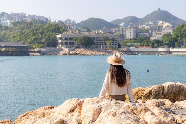 Photo travel woman sit on the rock and enjoy the sea view