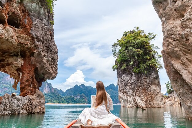 Travel Woman Sitting on Boat near Famous Three rocks in Khao Sok Park, Thailand