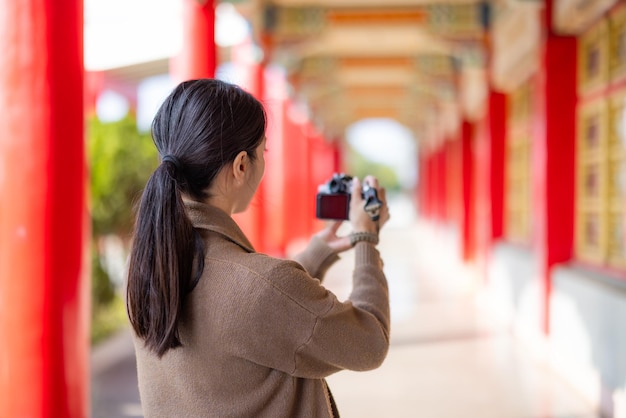 中国の寺院でデジタルカメラを使って写真を撮る女性旅行者