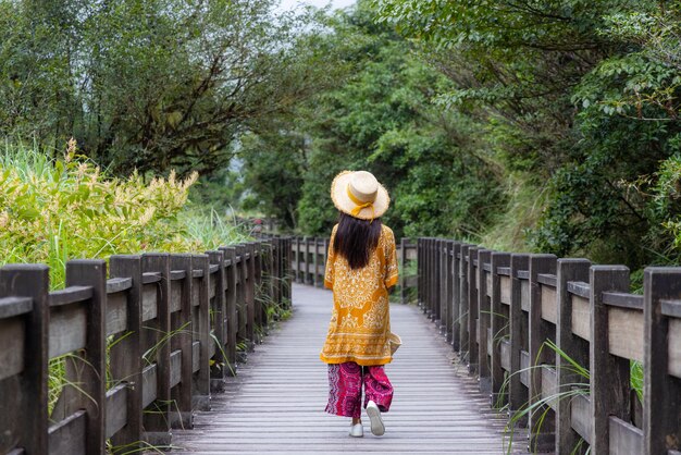 森の木の道を歩く女性旅行者