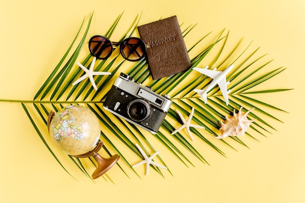 Photo traveler accessories concept on yellow background retro camera model plane airplane sunglasses passp