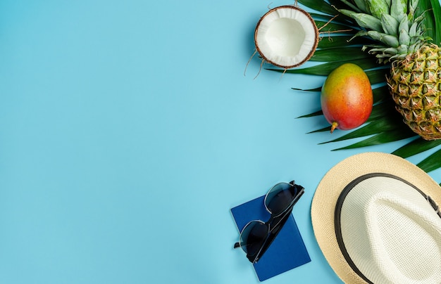 Traveler accessories and exotic fruits on blue background. Top view, copy space.