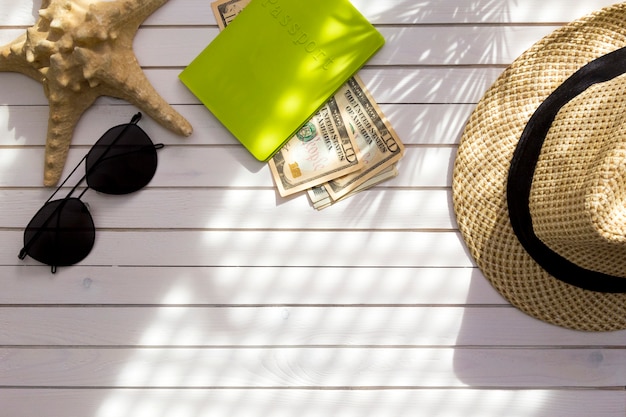 Traveler accessories - passport with cash money US dollars, hat, tropical palm leaf branches shadow. 