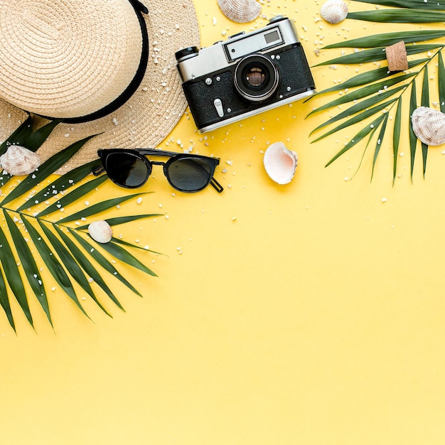 Traveler accessories tropical palm leaf branches on yellow background with empty space for text Summer background Flat lay top view