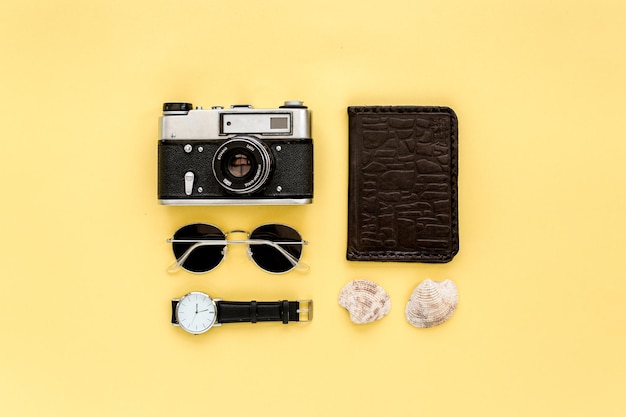 Traveler accessories on yellow background with camera and sunglasses Flat lay top view Summer background