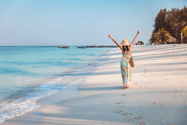 La donna asiatica del viaggiatore si rilassa e viaggia sulla spiaggia in tailandia