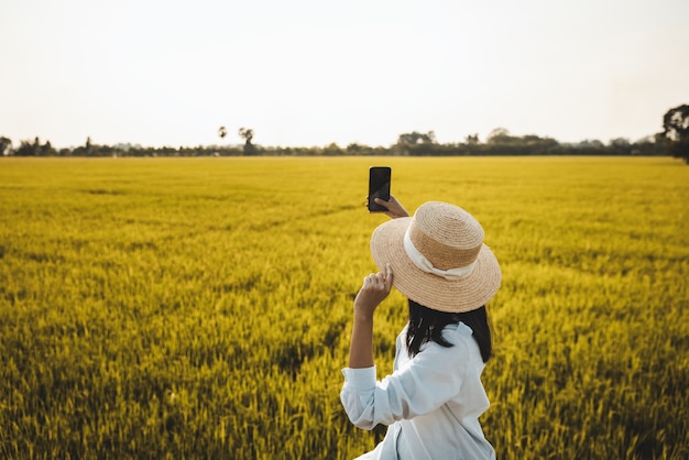 Traveler asian woman using mobile phone on rice field in farm at nakhon nayok thailand