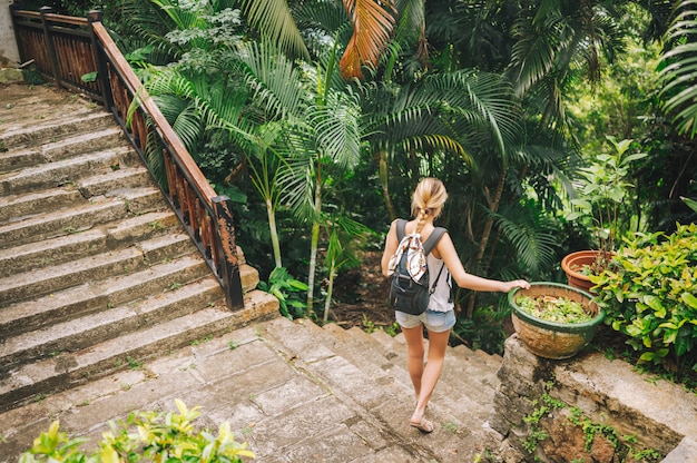 Traveler blonde backpacker woman  walking and discovering jungle tropical park, Travel adventure nature in China, Tourist beautiful destination Asia, Summer holiday vacation journey trip concept