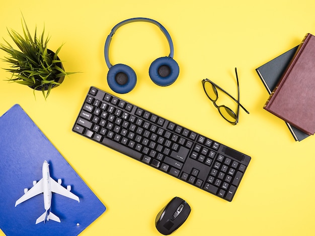 Traveler businessman  top view of his yellow desktop, headphones, clipboard, pot of grass