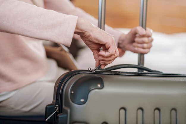 Traveler. Close up picture of female hand zipping suitcase