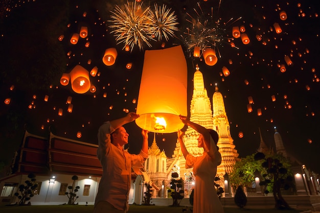 Traveler couple enjoy yeepeng floating lantern in loi kratong festival at Arun temple