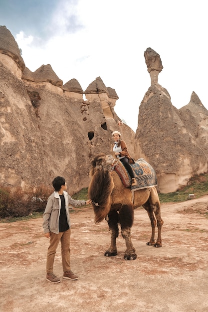 Traveler couple with camel at Goreme fairy chimneys , Cappadocia. Nevsehir Province. Turkey.