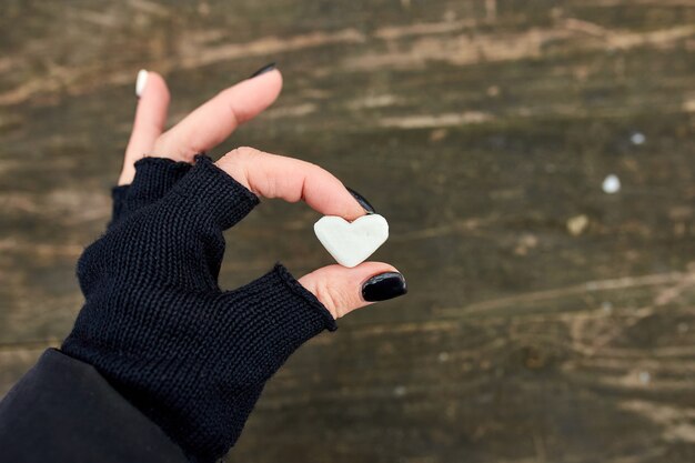 Ragazza viaggiatore in guanti neri tenere in mano marshmallow a forma di cuore