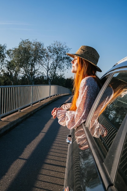 Traveler girl leaning out of car window