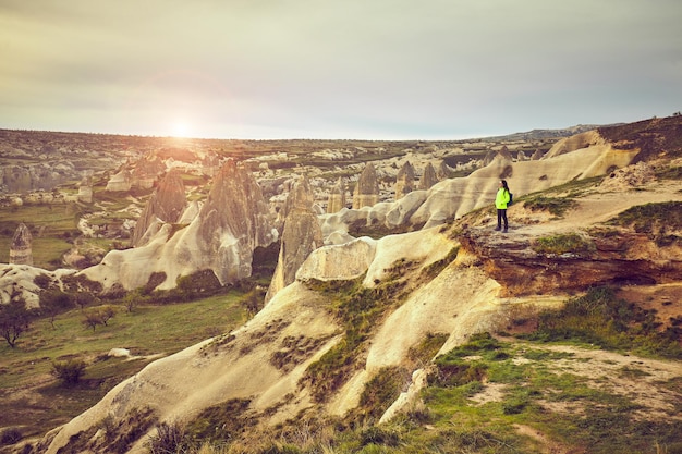 Traveler girl standing on cliff above mountains valley landscape