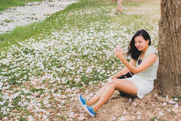 Traveler girl using smart phone in the flower garden background with vintage filter