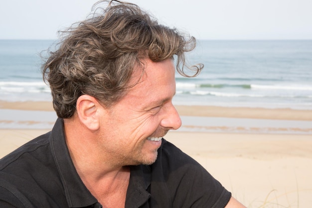 Traveler handsome hipster man sitting on white sand, beautiful beach, enjoying amazing view sunset