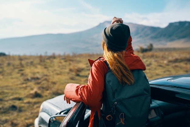 Traveler in a hat with a backpack near the car door in nature.
high quality photo