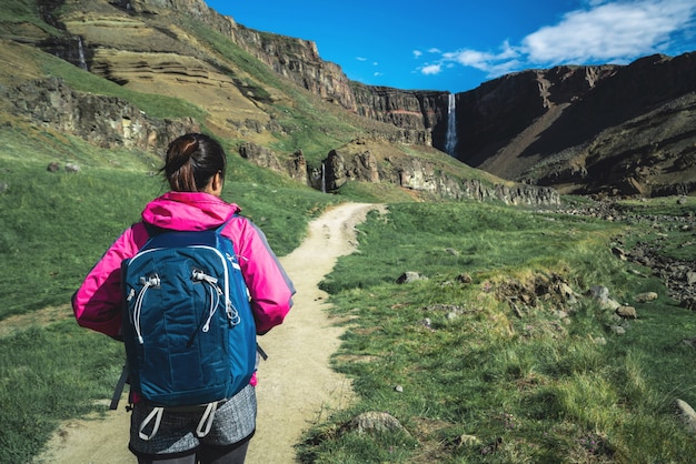 Traveler hiking at Hengifoss Waterfall, Iceland.