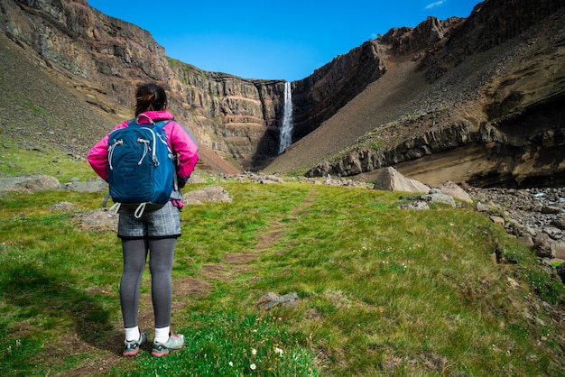 Traveler hiking at Hengifoss Waterfall, Iceland.