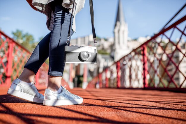 Photo traveler holding photocamera near the legs standing on the footbridge in lyon old town