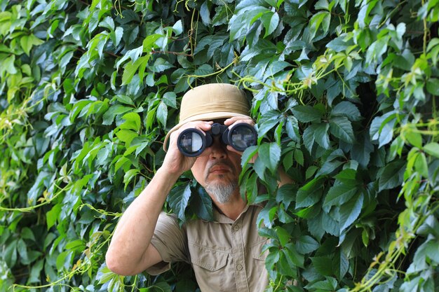 traveler looks through binoculars in the leaves