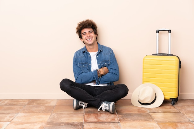 Traveler man his suitcase sitting on the floor laughing