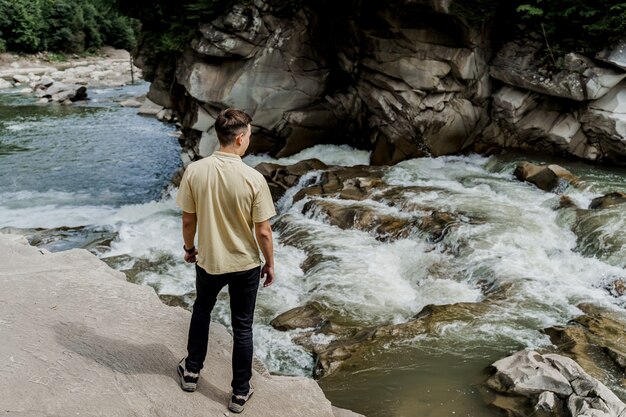 Uomo del viaggiatore sulla roccia vicino alla cascata.