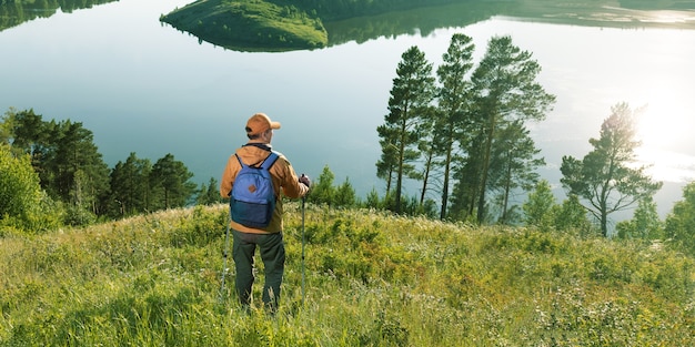 山の湖に立っている旅行者の男。旅行ライフスタイルハイキングアドベンチャーコンセプト。バナー。