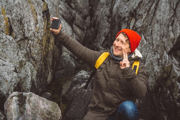 Traveler man taking selfportrait with a smartphone against the background of mountains and rocks