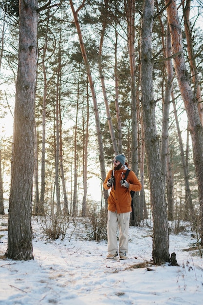 Viaggiatore uomo con zaino escursioni in inverno paesaggio forestale innevato concetto di stile di vita di viaggio avventura vacanze attive tempo freddo all'aperto nel selvaggio