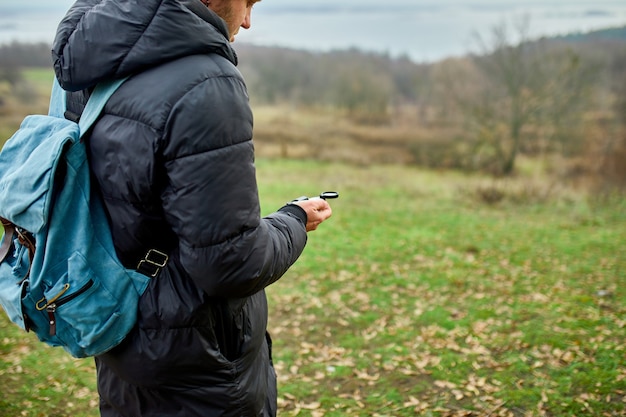 Путешественник с рюкзаком с компасом в руке на фоне гор природы