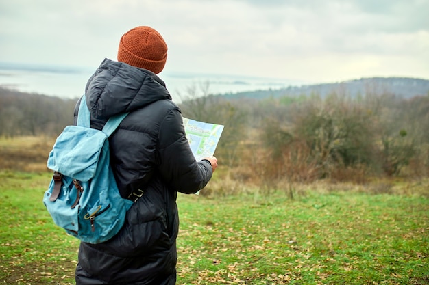 Uomo del viaggiatore con lo zaino con la mappa in mano su una parete del fiume delle montagne della natura, concetto di viaggio, vacanze e concetto di escursionismo di stile di vita