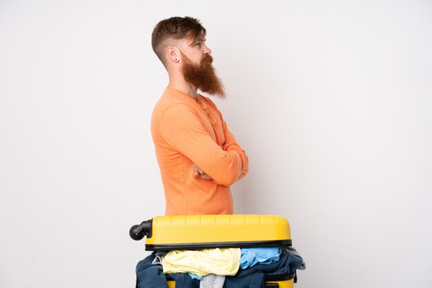 Traveler man with a suitcase full of clothes over isolated white looking side