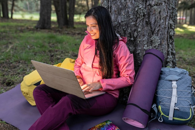 Traveler mature woman in forest with laptop biologist using\
laptop in camping nature