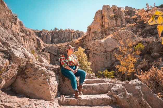 Traveler person taking a second wind sitting on some stone steps in a mountainous landscape