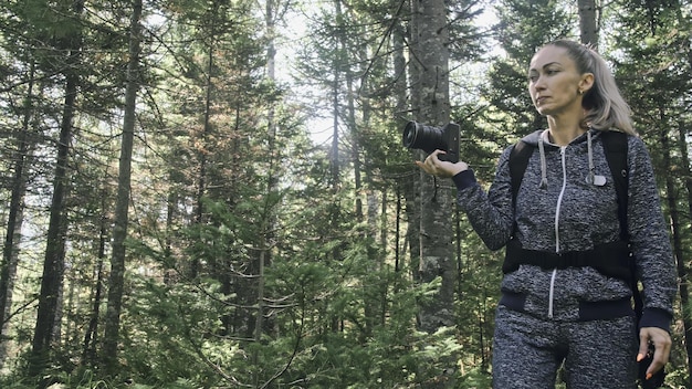 숲에서 경치를 촬영하는 여행자 한 백인 여성