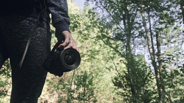 Traveler photographing scenic view in forest One caucasian woman shooting close up look Girl hold dslr mirrorless camera in his hand Outdoor