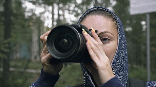 Traveler photographing scenic view in forest One caucasian woman shooting close up look Girl take photo video on dslr mirrorless camera Professional photographer travel with backpack Outdoor