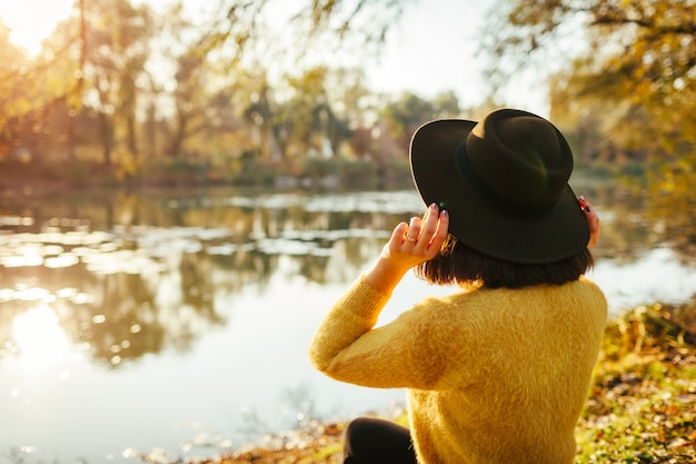 Traveler relaxing by autumn river at sunset