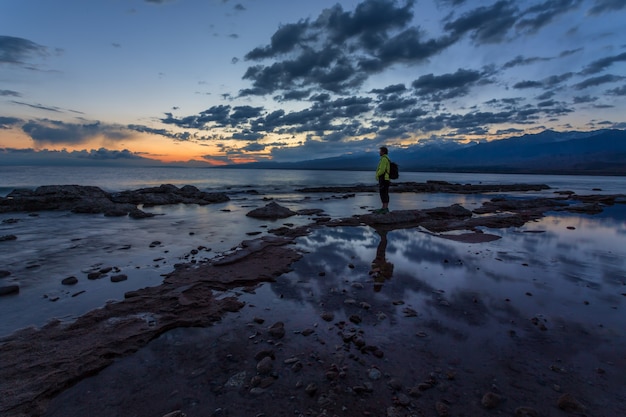 Traveler on the shore of a mountain lake