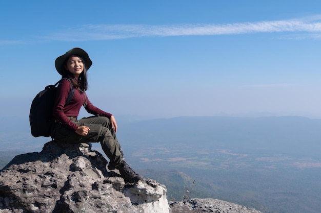 A traveler sits on a rock on a high mountain with a beautiful view of the sky