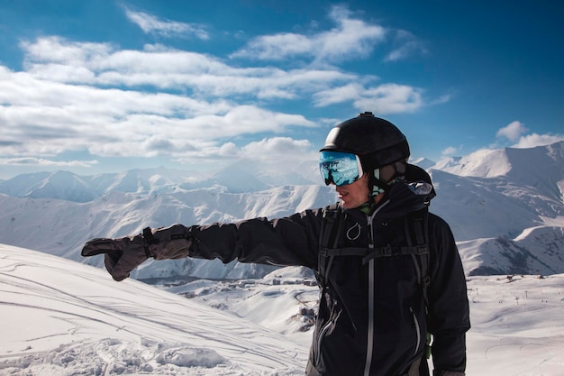 A traveler in a ski mask points to the left towards the high mountains of the Caucasus