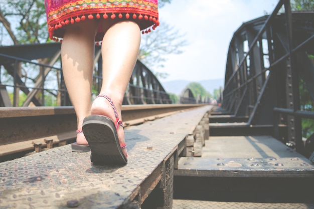 traveler on sneakers shoe while walking at railway bridge