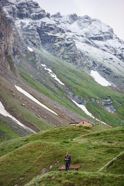 Viaggiatore in piedi accanto alla panchina nella valle di montagna