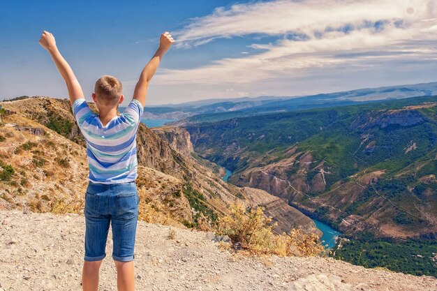 Traveler teenager boy hands raised mountains landscape