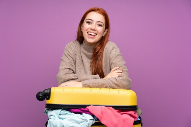 Traveler teenager girl with a suitcase full of clothes laughing