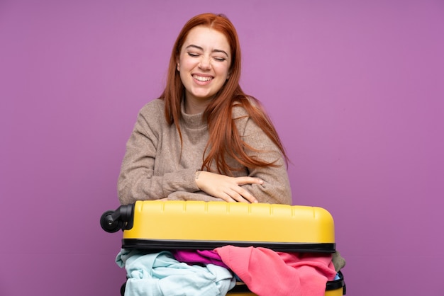 Traveler teenager woman with a suitcase full of clothes laughing