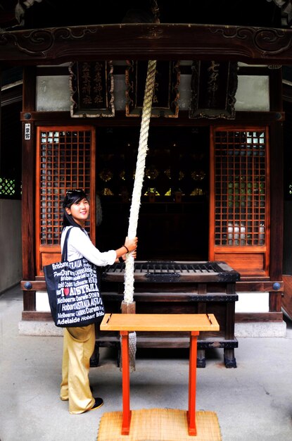 2015年7月10日に大阪城公園の北国神社エリアにある小さな神社で鐘の儀式や祈りのメリットを振る旅行者のタイの女性